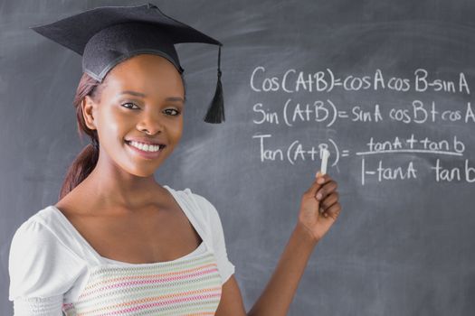 Student smiling while showing the blackboard in a classroom