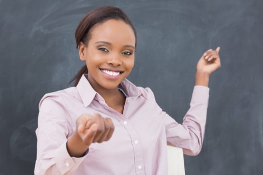 Black teacher smiling while showing the blackboard in a classroom