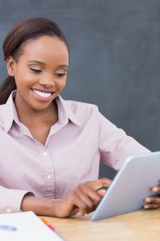 Teacher smiling while using a tablet computer in a classroom