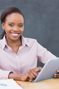 Teacher looking at camera while using a tablet computer in a classroom