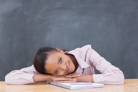 Black woman leaning her head on desk while smiling in a classroom