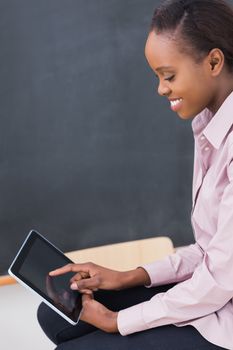 Teacher touching a tablet computer while looking it in a classroom