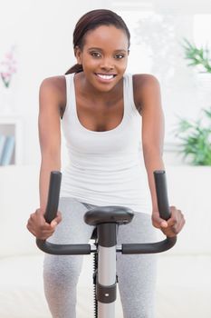 Black woman doing exercise bike in a living room