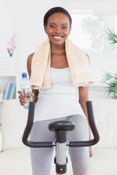 Black woman on bike holding a water bottle in a living room