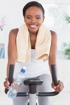 Black woman sitting on an exercise bike in a living room