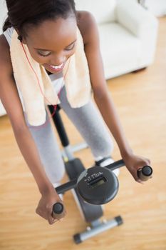 High view of a black woman sitting on an exercise bike in a living room