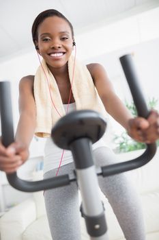 Front view of a black woman doing exercise bike in a living room