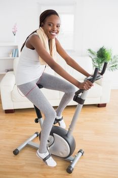 Black woman doing exercise bike with headphones in a living room