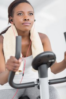 Concentrated woman doing exercise bike while listening music in a living room