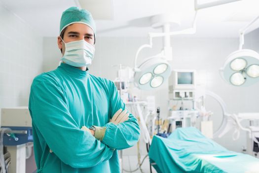Serious surgeon standing with arms crossed in an operating theatre