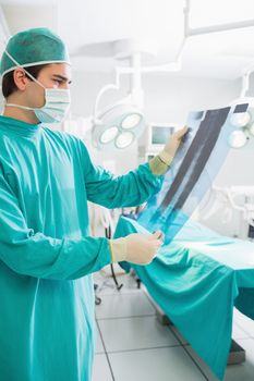 Surgeon holding a X-ray while looking at it in an operating theatre