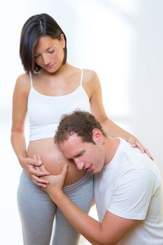 Beautiful pregnant woman with husband couple hearing baby on mother belly