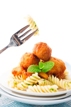 Fusilli on fork, meatball fusilli as background