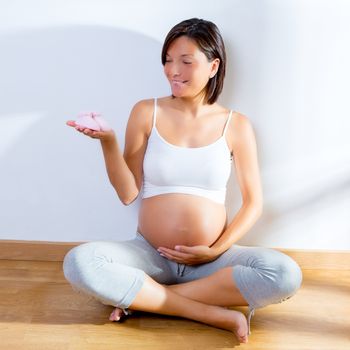 Beautiful pregnant woman with baby pink shoes on her hand happy at home