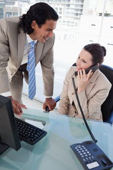 Portrait of a businesswoman on the phone while working with an employee in an office