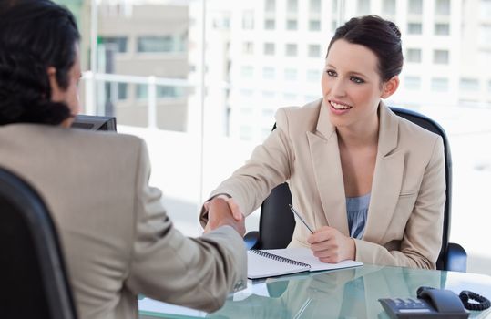 Manager shaking the hand of a male applicant in her office