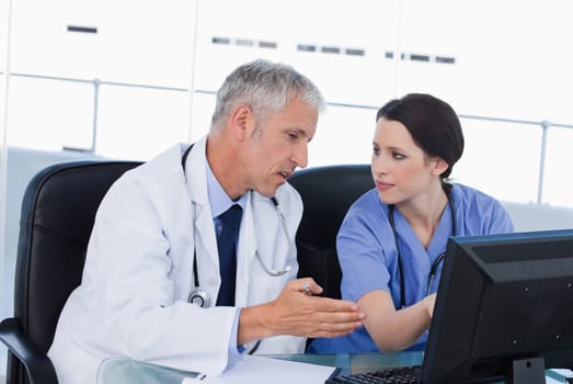 Serious medical team working with a computer in an office