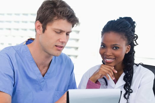 Smiling doctors looking at a document in an office