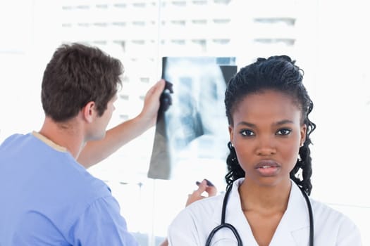 Male doctor looking at a of X-ray while his colleague is posing in an office