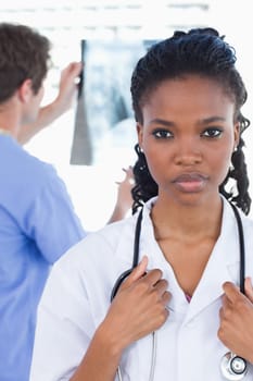 Portrait of a doctor looking at a of X-ray while his colleague is posing in an office