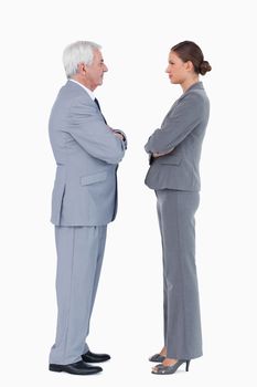 Businesspartner standing face to face with arms folded against a white background