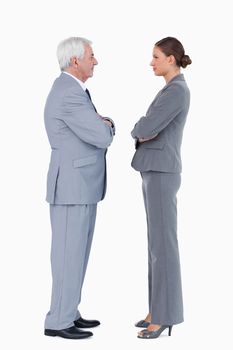 Businesspartner standing face to face with arms folded against a white background