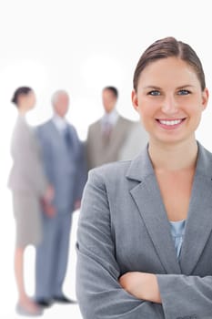 Smiling businesswoman with her colleagues behind her against a white background