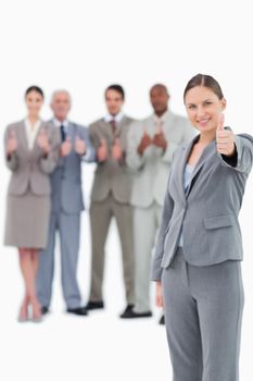 Tradeswoman with thumb up and colleagues behind her against a white background