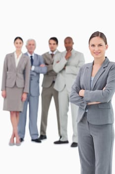 Saleswoman with arms folded and her team behind her against a white background