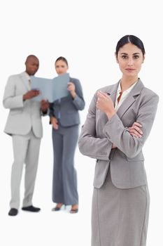 Serious saleswoman with colleagues behind her against a white background