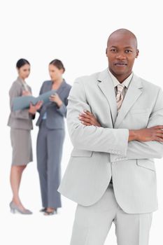 Businessman with crossed arms and colleagues behind him against a white background