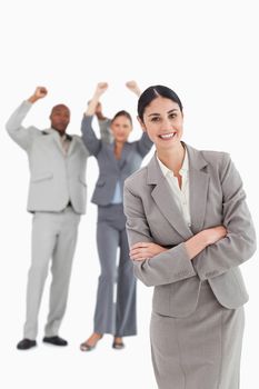 Smiling businesswoman with cheering colleagues behind her against a white background