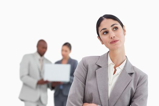 Daydreaming businesswoman with colleagues behind her against a white background