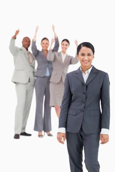 Smiling saleswoman with cheering team behind her against a white background