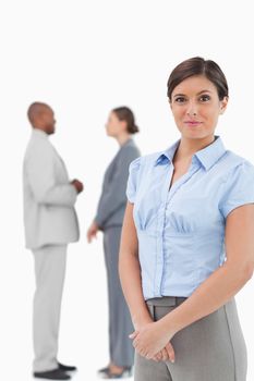 Saleswoman with talking associates behind her against a white background