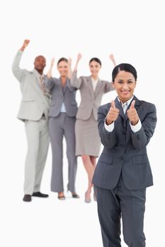 Saleswoman with cheering team behind her giving thumbs up against a white background