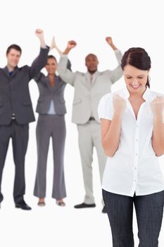 Triumphant businesswoman with cheering colleagues behind her against a white background