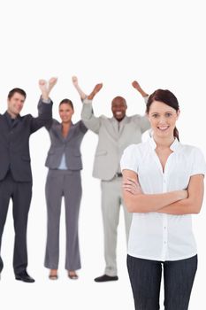 Smiling businesswoman with cheering co-workers behind her against a white background