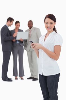 Tradeswoman with mobile phone and colleagues behind her against a white background