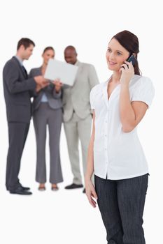 Tradeswoman with colleagues behind her on the phone against a white background