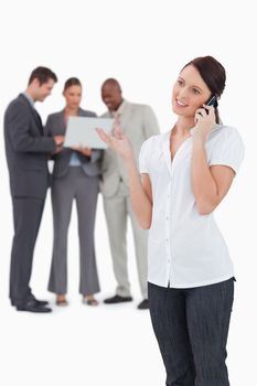 Tradeswoman on the phone with colleagues behind her against a white background