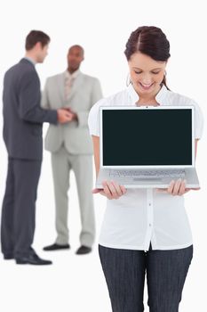 Businesswoman showing notebook with colleagues behind her against a white background
