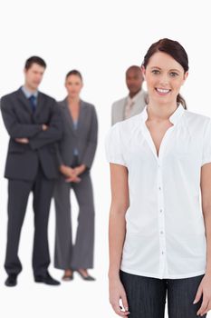 Smiling businesswoman with three co-workers behind her against a white background