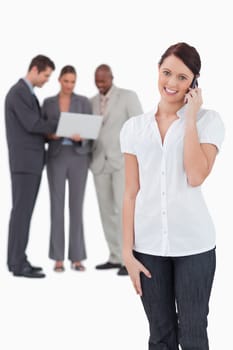 Saleswoman with associates behind her on the phone against a white background