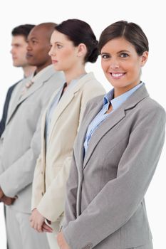 Smiling businesswoman standing next to her associates against a white background