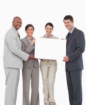 Smiling salesteam holding blank sign together against a white background