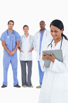 Female doctor taking notes with staff members behind her against a white background