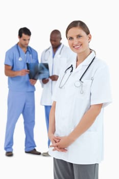 Smiling doctor with colleagues and x-ray behind her against a white background