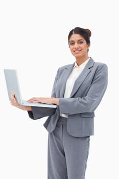 Smiling businesswoman using notebook while standing against a white background