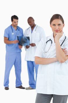 Thinking doctor with colleagues behind her against a white background